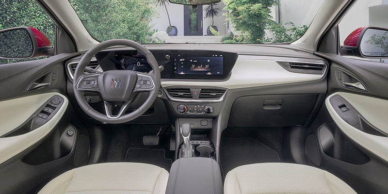 Interior view of a Buick vehicle showing the front cabin, including the steering wheel with Buick logo, digital dashboard display, center touchscreen infotainment system, and climate controls with a clean, modern design.
