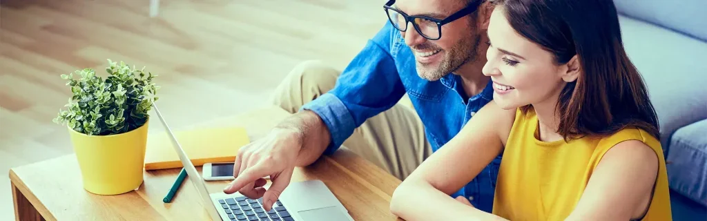 Couple reviewing information on a laptop at home.
