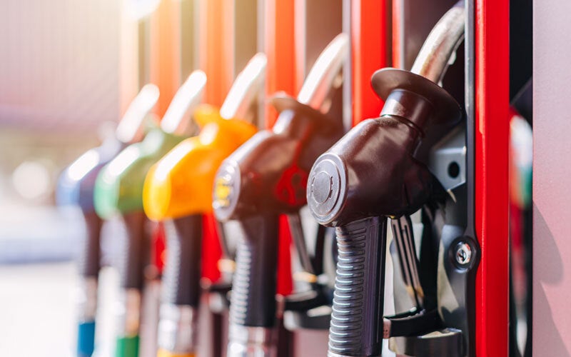 A row of colorful fuel pump nozzles at a gas station.