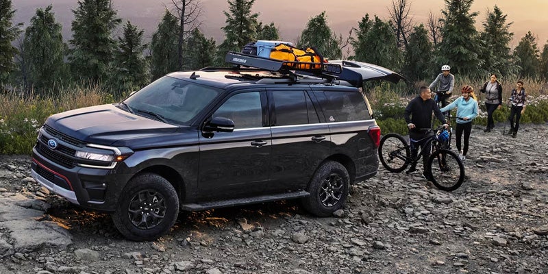 Family outdoors enjoying time together riding bikes by their 2025 Black Ford Expedition