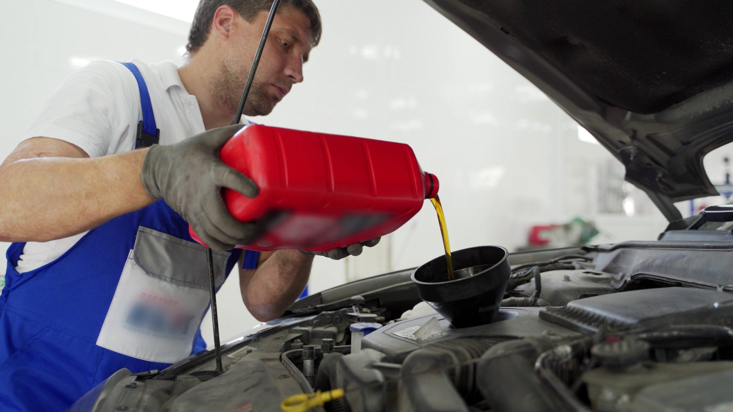 Auto Technician pouring engine oil into engine