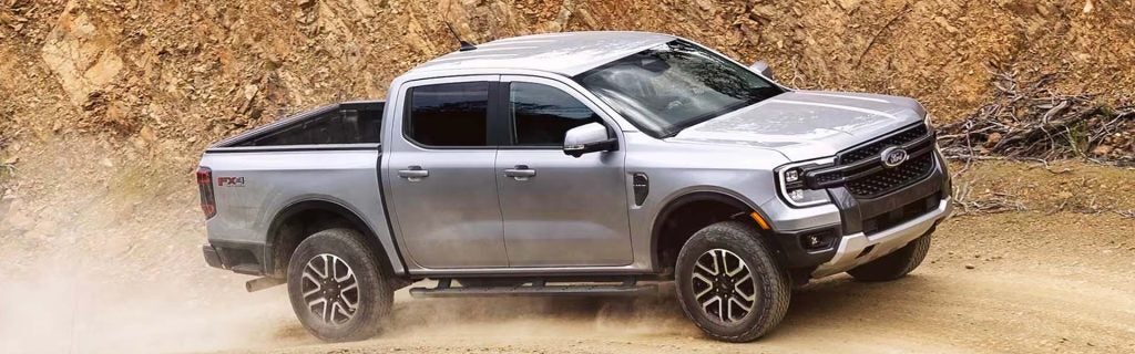 Silver Ford Ranger pickup driving off-road.