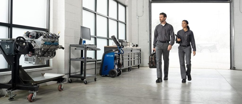 Two technicians walking through a modern auto repair workshop.