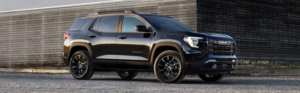 A black 2025 GMC Terrain parked on rocky gray dirt near a concrete structure at sunset, near Seminole, OK.