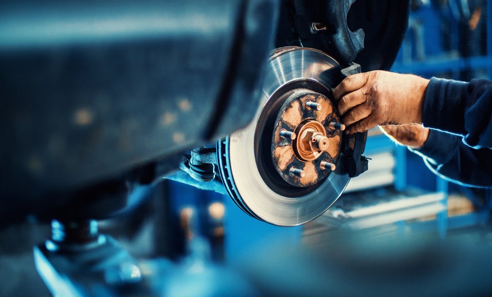 Closeup of unrecognizable mechanic replacing car brake pads.