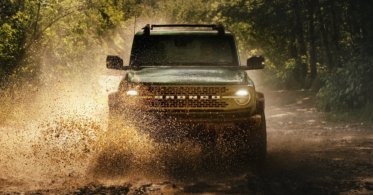 Ford Bronco driving through the mud in the middle of the forest