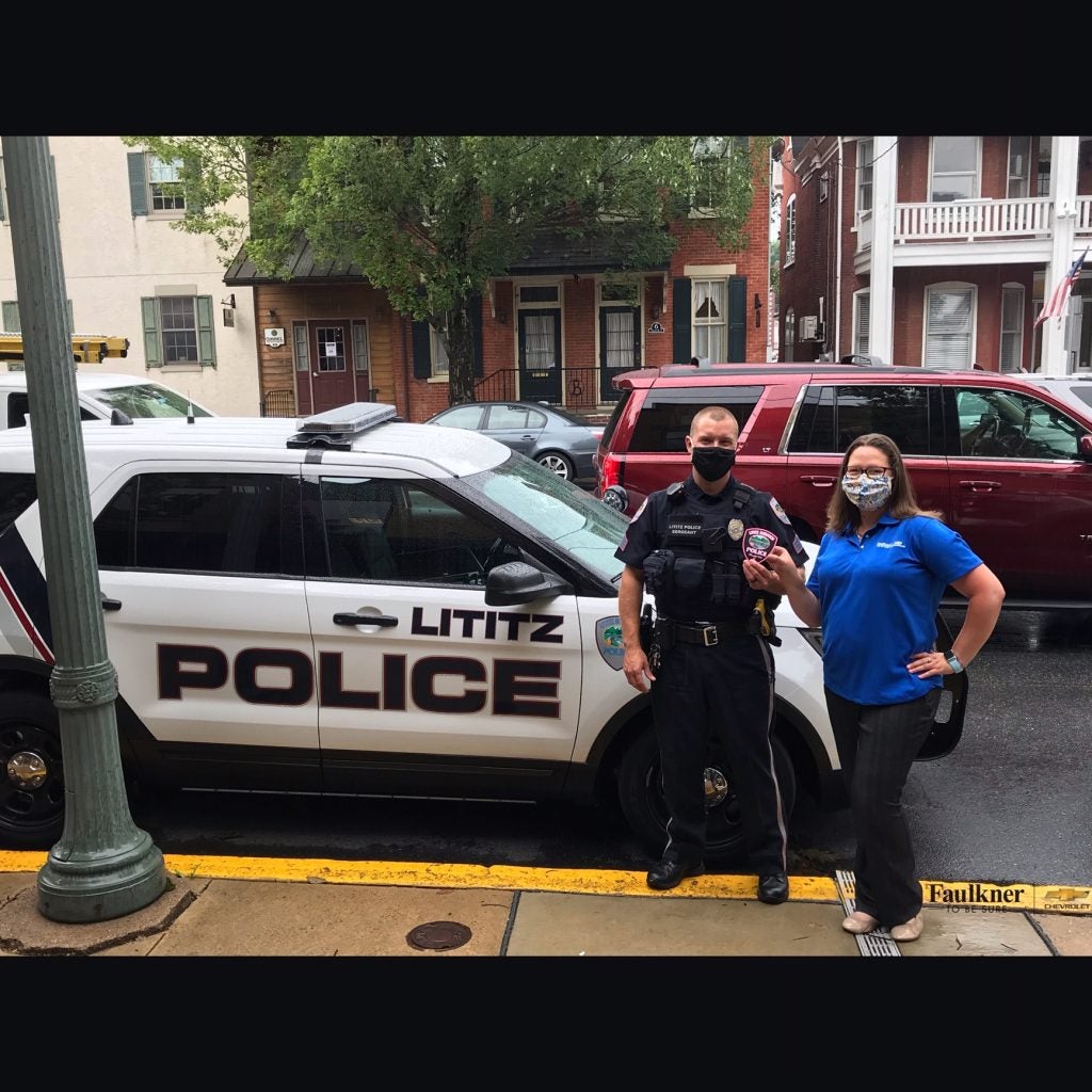 two people standing next to a police vehicle