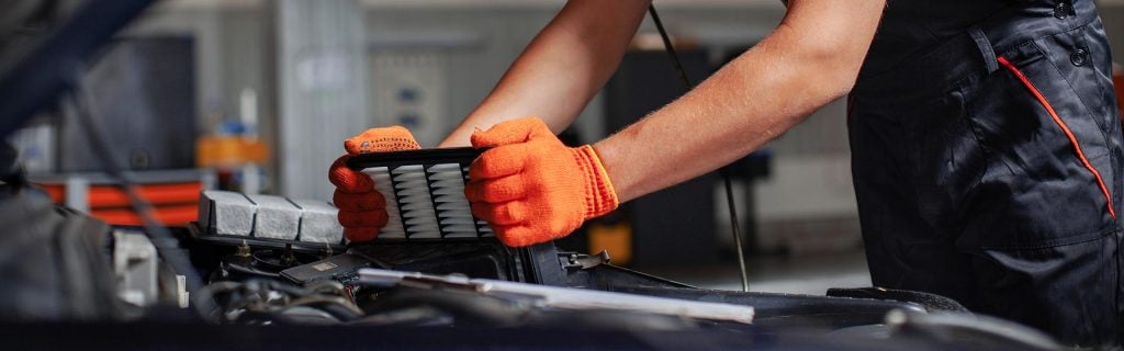 Mechanic replacing a car engine air filter in a service bay