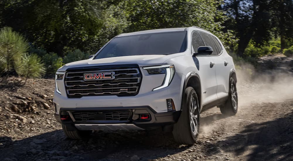 A white 2025 GMC Acadia AT4 off-roading on a trail