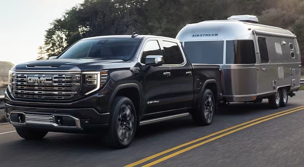 A black 2025 GMC Sierra 1500 Denali towing a trailer.