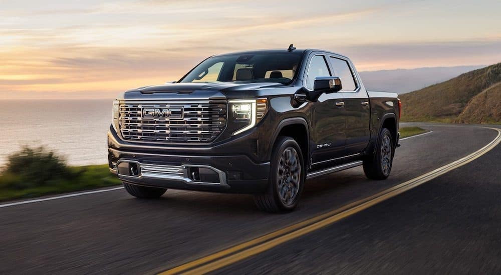A black 2022 GMC Sierra 1500 driving down a winding road from a used GMC dealer.