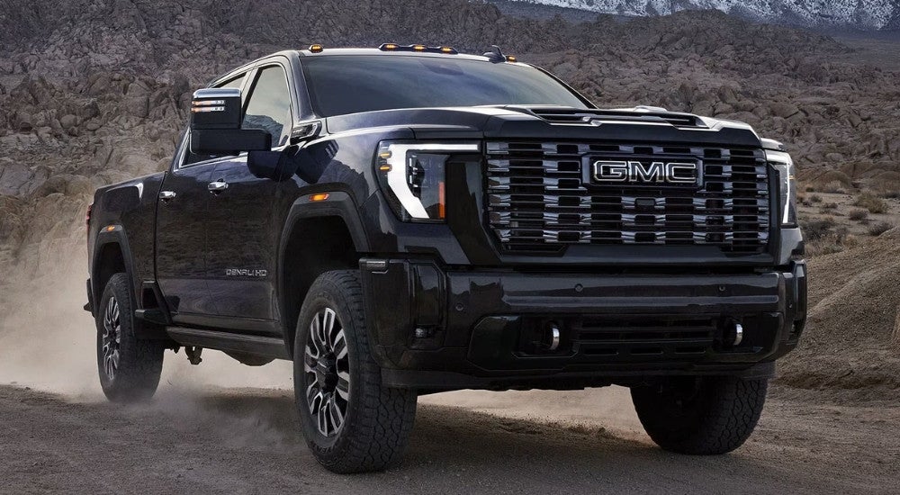 A black 2025 GMC Sierra 2500 HD for sale on a dusty dirt road.