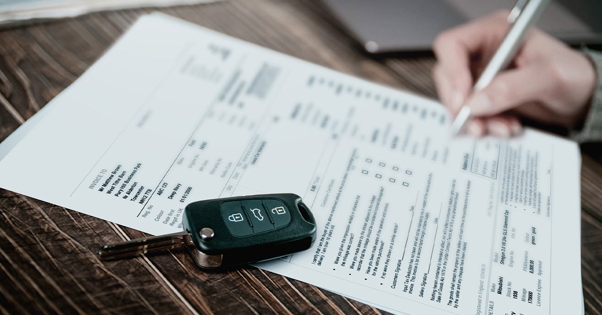 Customer filling out financing paperwork with car keys on the table.