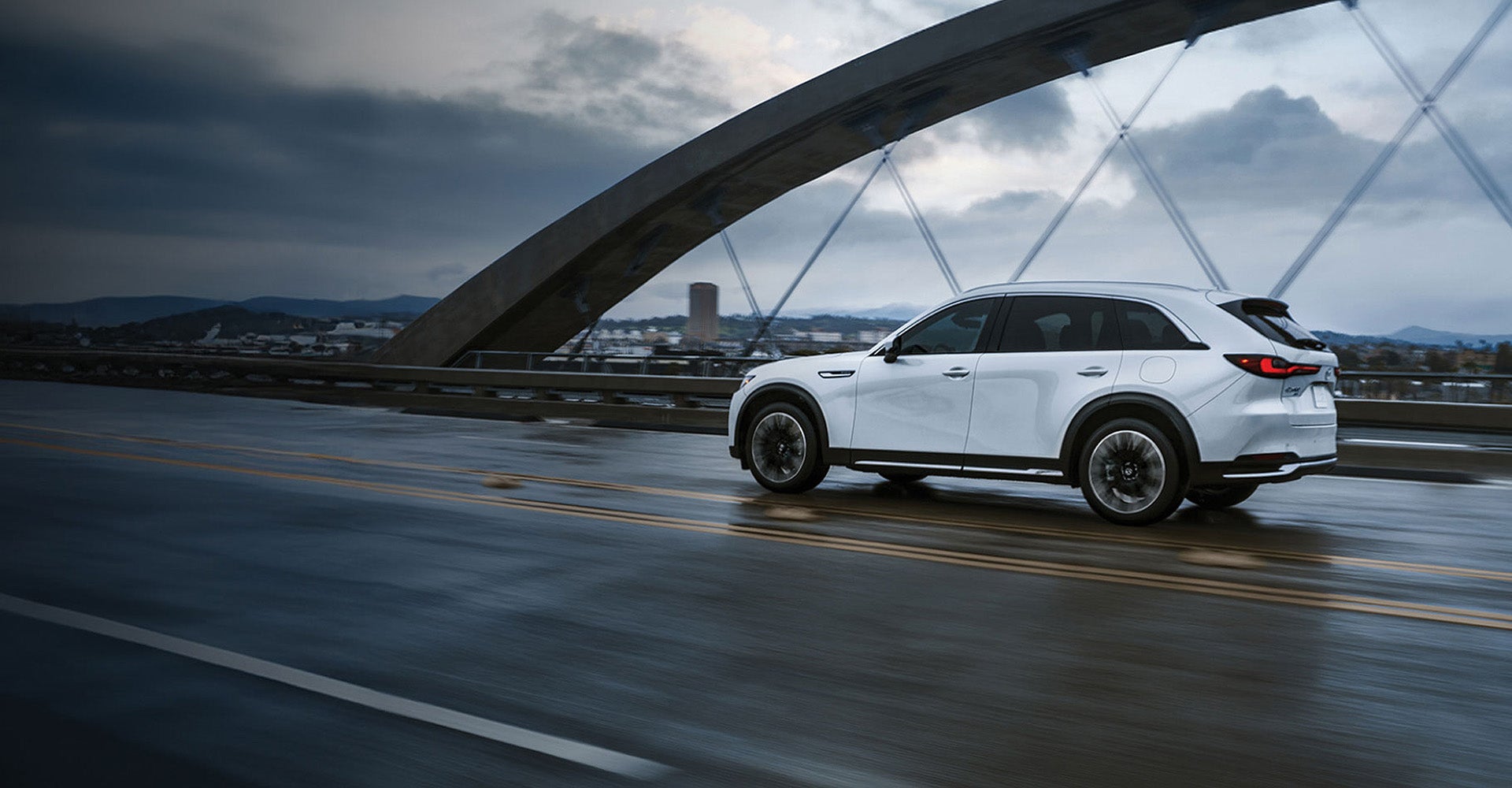 White 2026 Mazda CX-90 driving over a bridge near Longview, TX
