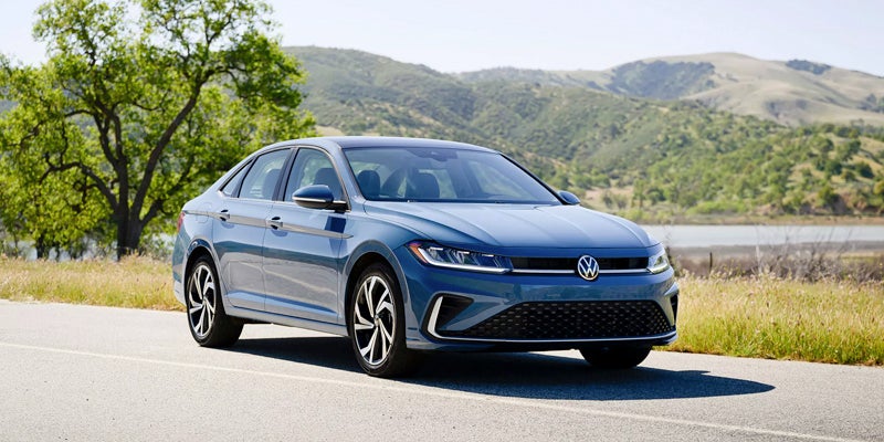 vw jetta standing on a road surrounded by mountains 