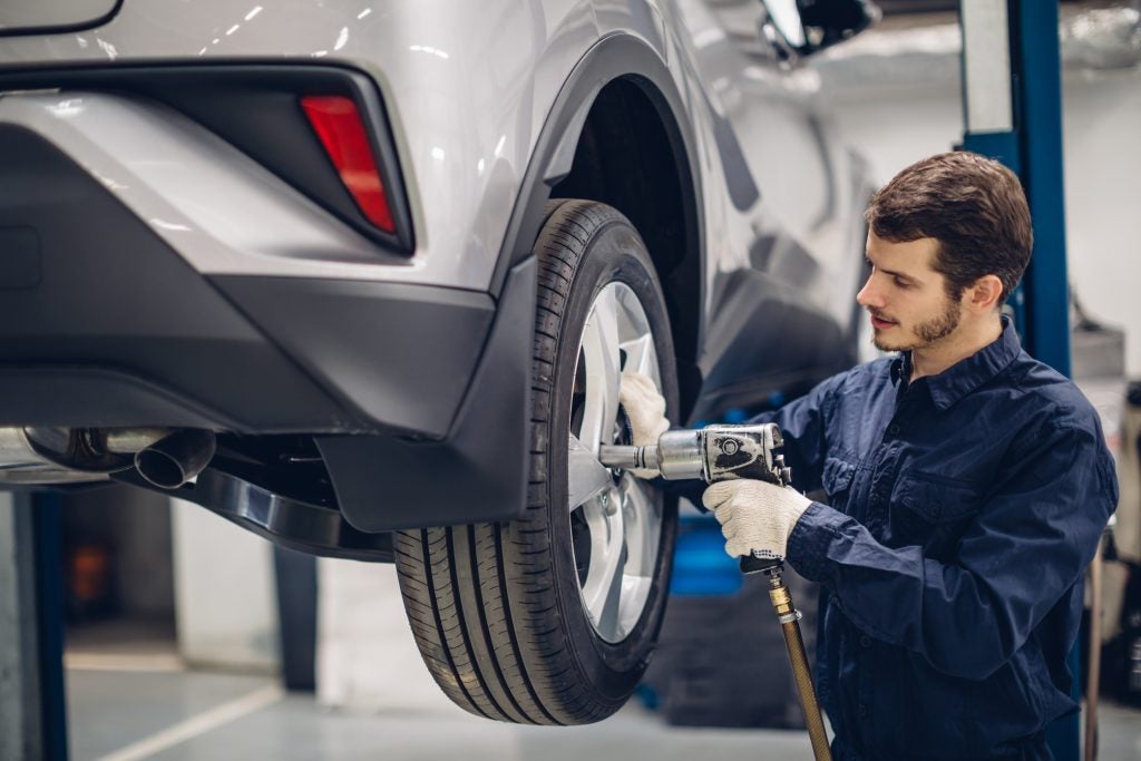 Automotive technician servicing a vehicle wheel during tire maintenance at a repair shop.