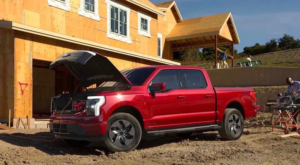 A red 2022 Ford F-150 Lightning is shown at a construction site.
