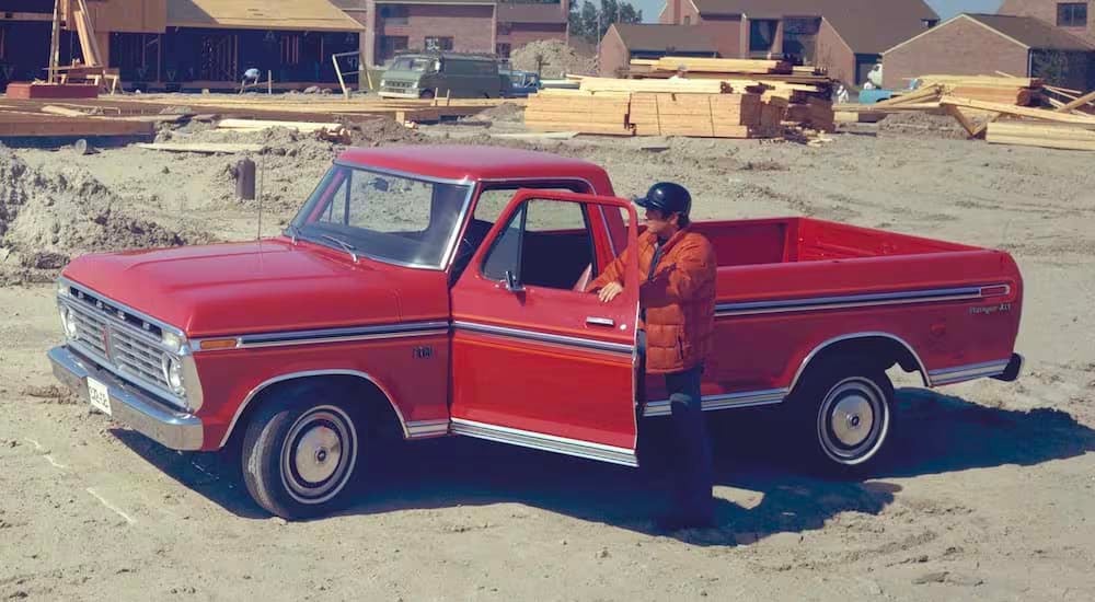 A red 1976 Ford F-150 is shown from the side while parked on a job site.