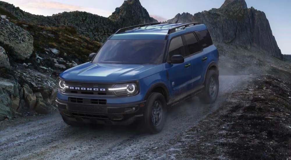A blue 2024 Ford Bronco Sport Big Bend is shown descending a trail after leaving a Ford dealer near…