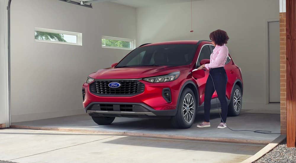 A red 2023 Ford Escape Hybrid is shown charging in a garage after leaving a Ford Escape dealer.