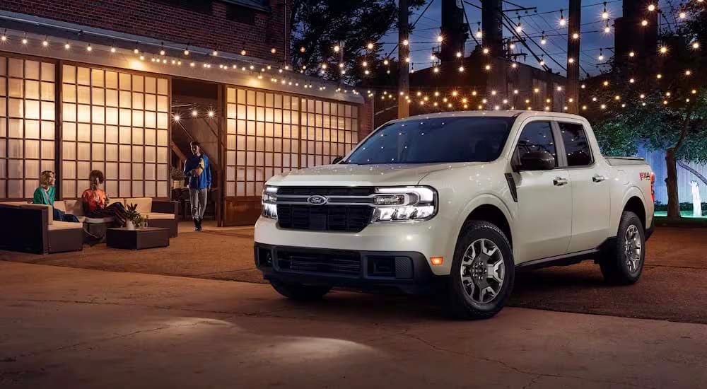 A white 2024 Ford Maverick is parked in a driveway underneath lights.