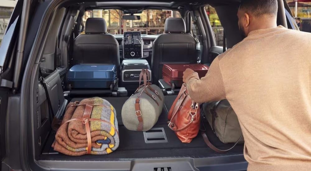 A person is shown stowing luggage in the trunk of a 2024 Ford Expedition.