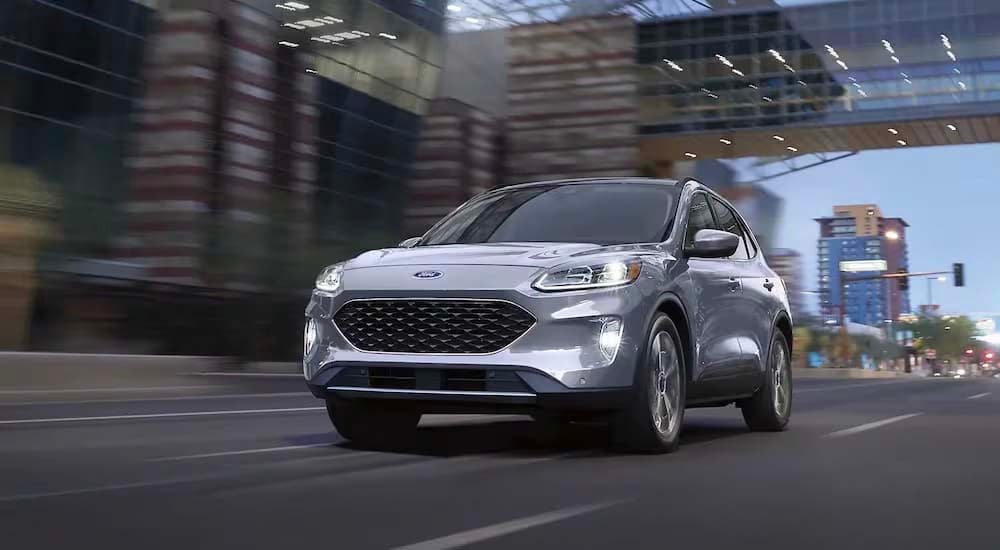 A grey 2022 Ford Escape Titanium Hybrid is shown driving in a city.