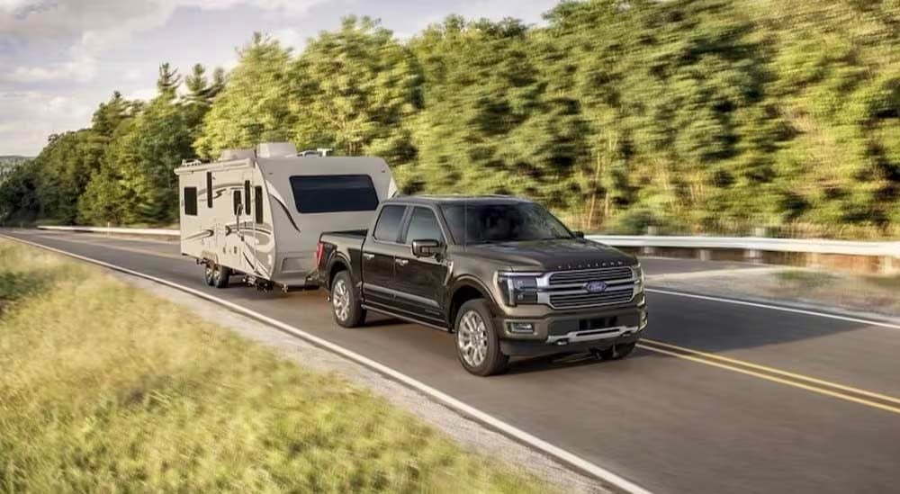  A black 2024 Ford F-150 Platinum is shown towing a trailer.