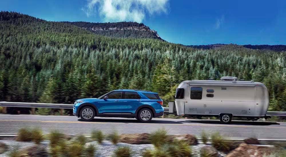 Ford Explorer for Sale - 2023 Ford Explorer Hybrid - Airstream.jpg A blue 2023 Ford Explorer Hybrid is shown from the side while towing a camper.
