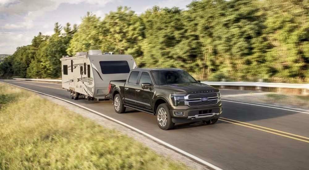 Used Truck Dealer - 2024 Ford F-150 Platinum Plus - Trailer.jpg A black 2024 Ford F-150 Platinum Plus is shown towing a trailer.