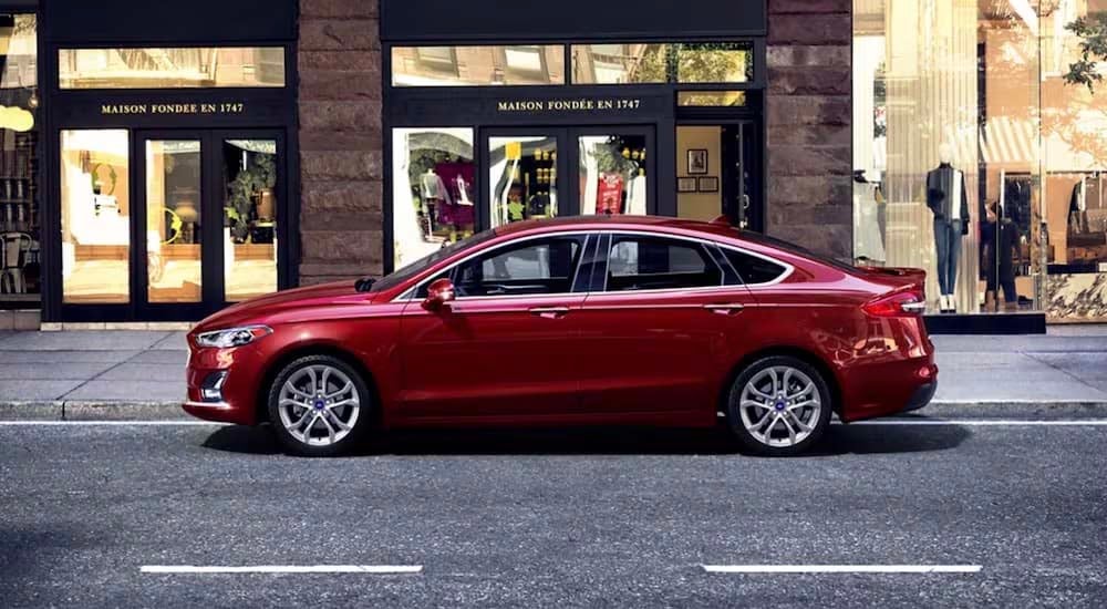 A red 2020 Ford Fusion is shown from the side on a city street.