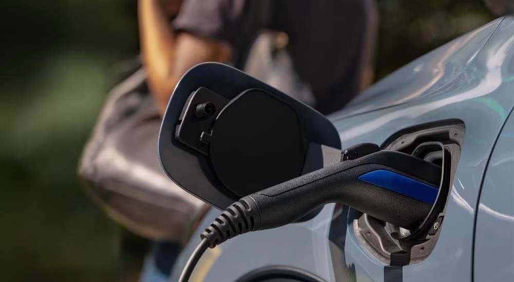 A close up shows a blue 2023 Ford Escape charging.