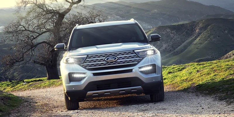 A white 2023 Ford Explorer King Ranch is shown from the front on a dirt trail.