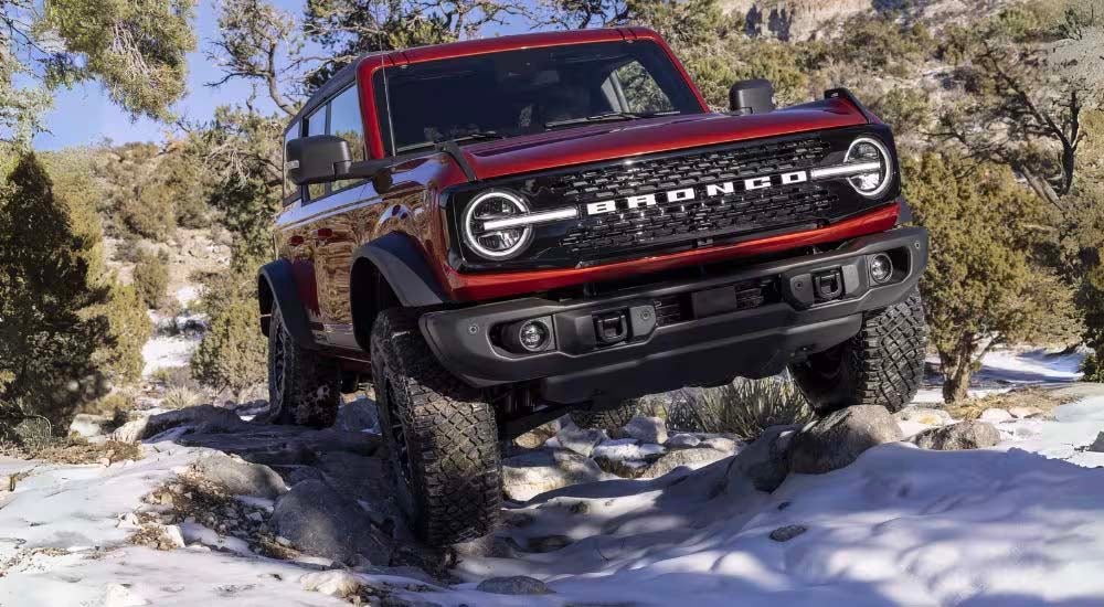 A red 2022 Ford Bronco is shown from the front while off-roading.