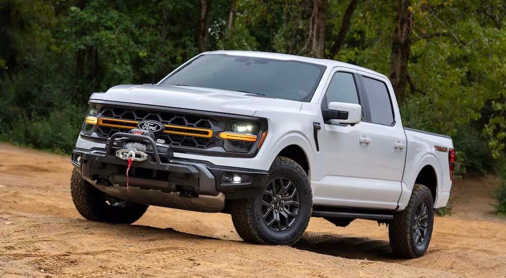 A white 2024 Ford F-150 Tremor is shown from the front at an angle while parked off-road after leavi…
