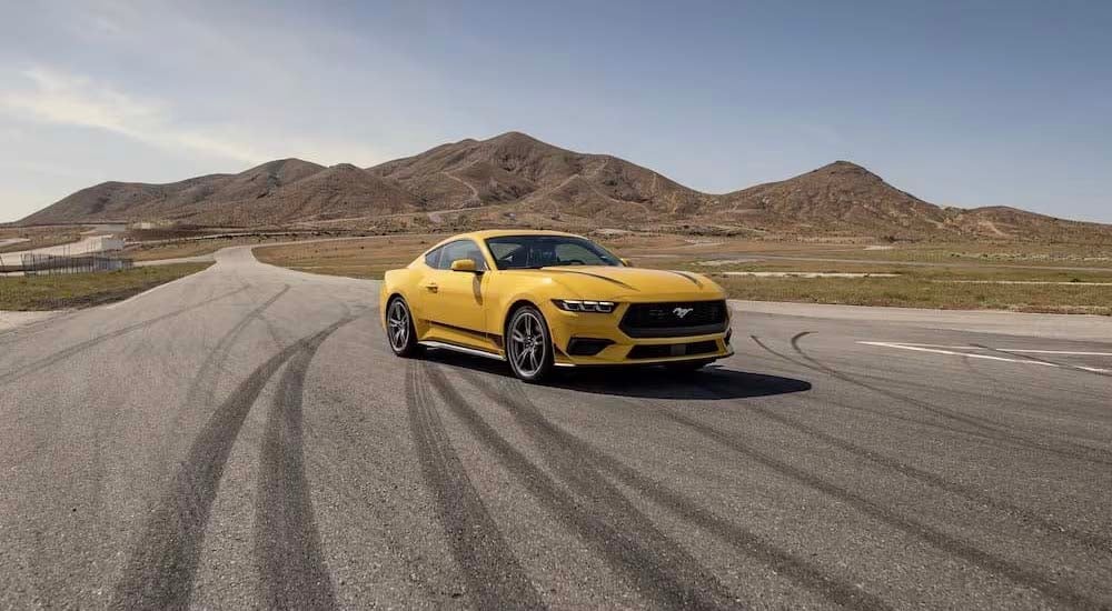 A yellow 2024 Ford Mustang is shown parked on a road.