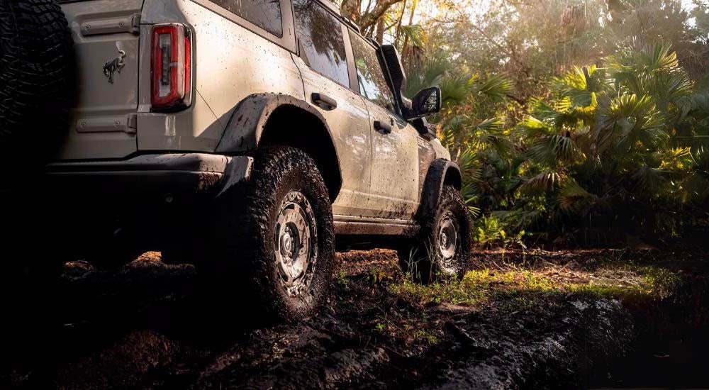 A 2022 Ford Bronco is shown from the rear with muddy tires after leaving a Ford Bronco dealership.