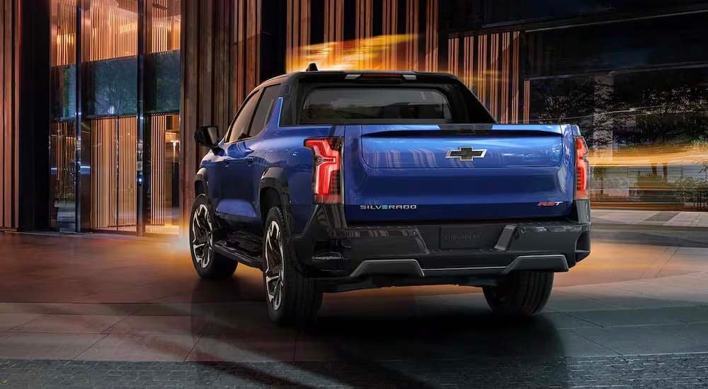 A blue 2024 Chevy Silverado EV RST is shown from the rear parked in a modern gallery.