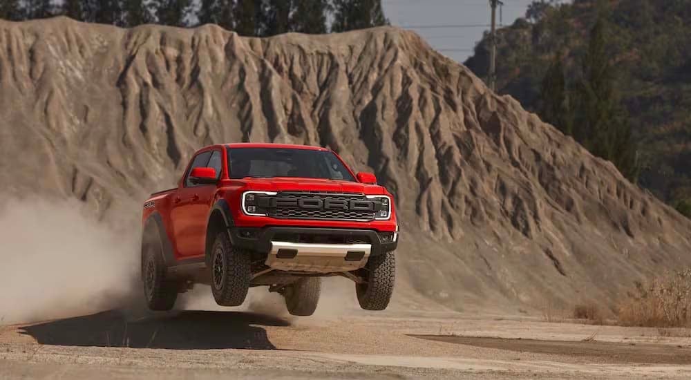 An orange 2024 Ford Ranger Raptor is shown from the front while jumping through the air