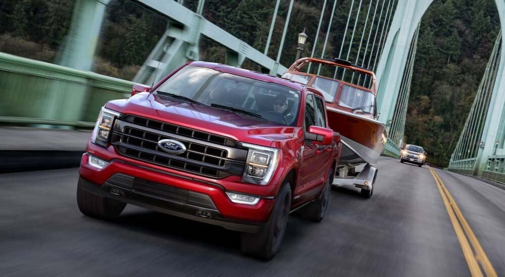A popular used truck for sale, a red 2021 Ford F-150, is shown driving on a bridge.
