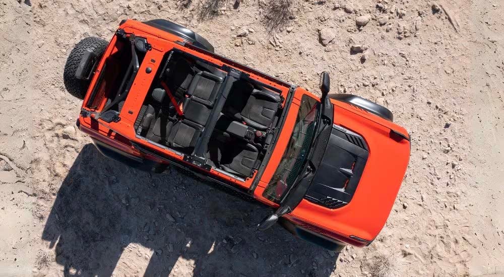 An orange 2022 Ford Bronco Raptor is shown from above parked in the desert