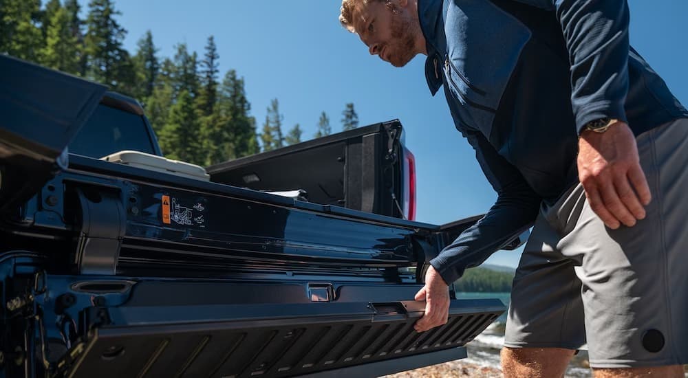 A perso closing the tailgate on a black 2026 GMC Sierra 1500.