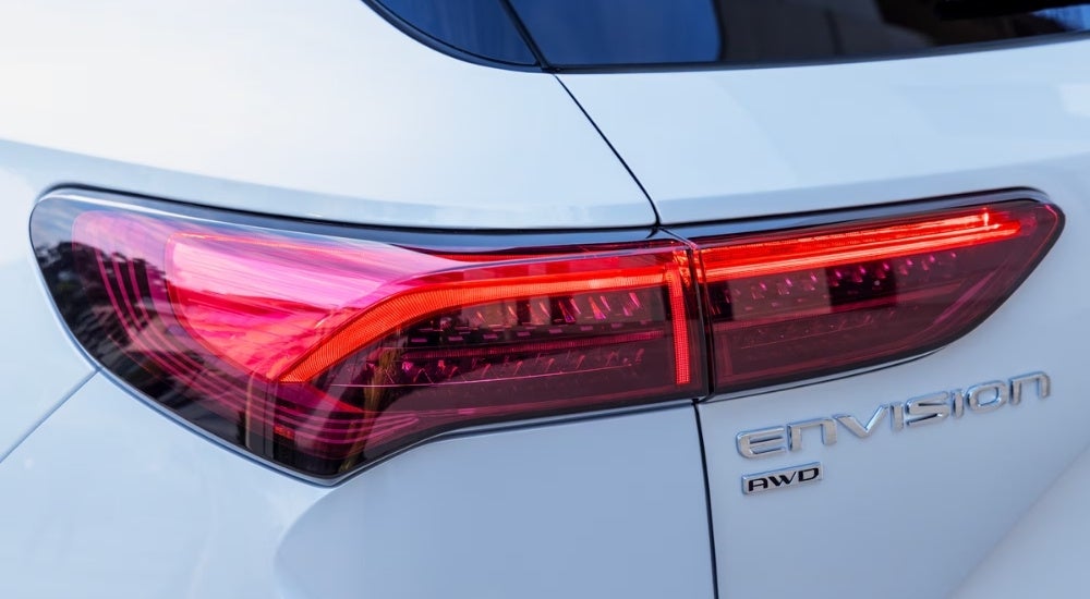 A close-up shows the driver side taillight on a white 2024 Buick Envision.