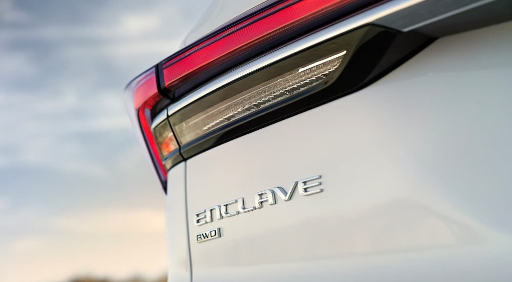 A close-up shows the driver side taillight on a white 2025 Buick Enclave.