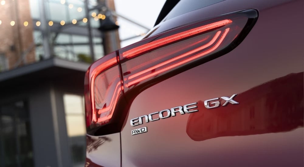 A close-up shows the driver side taillight on a red 2024 Buick Encore GX ST.