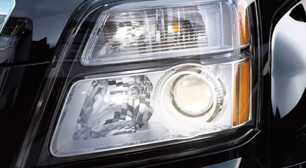 A close up shows driver side headlight on a black 2015 GMC Terrain.