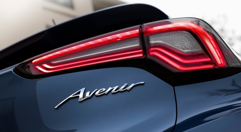 A close-up shows the passenger side taillight on a blue 2024 Buick Encore GX Avenir.