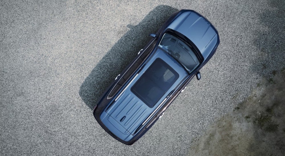 A blue 2024 GMC Acadia is shown parked on gravel from a high angle.