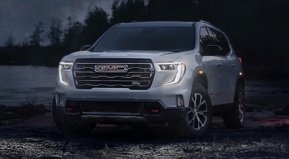 A silver 2024 GMC Acadia AT4 is parked off-road at night after visiting a GMC dealership near Minneapolis.