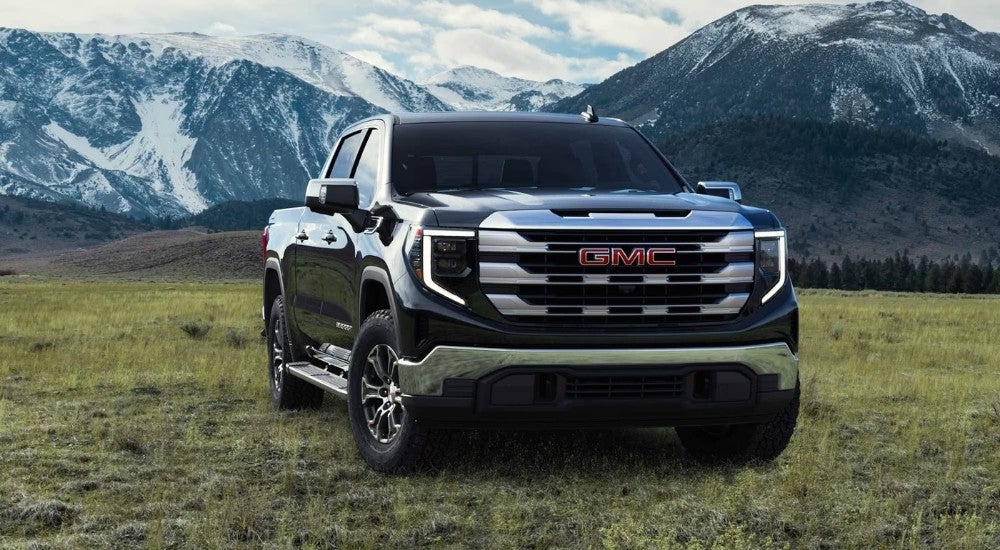 A black 2024 GMC Sierra 1500 SLE is shown parked on grass.